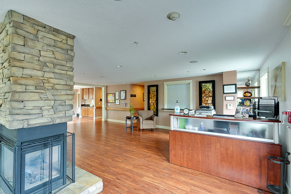 A spacious reception area with modern decor, featuring a fireplace and wooden flooring.