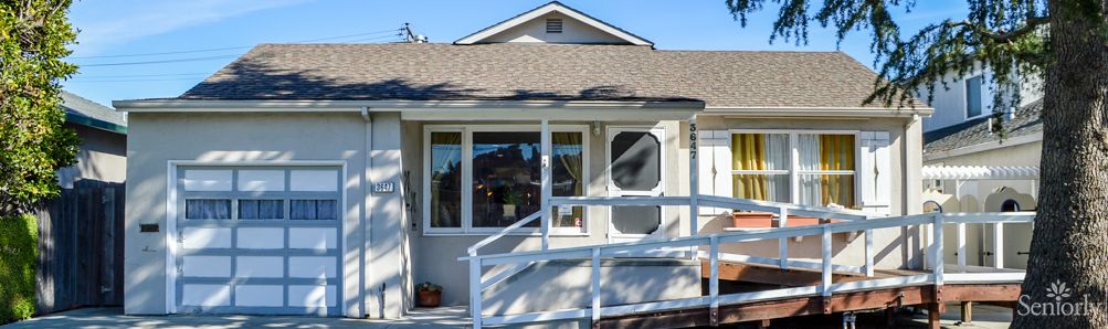 Front view of a house with a ramp and white railing leading to the entrance.