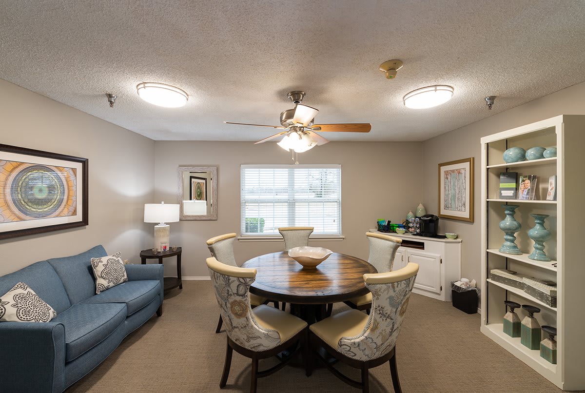 A cozy living and dining space featuring a round table with chairs, a sofa, and a ceiling fan.
