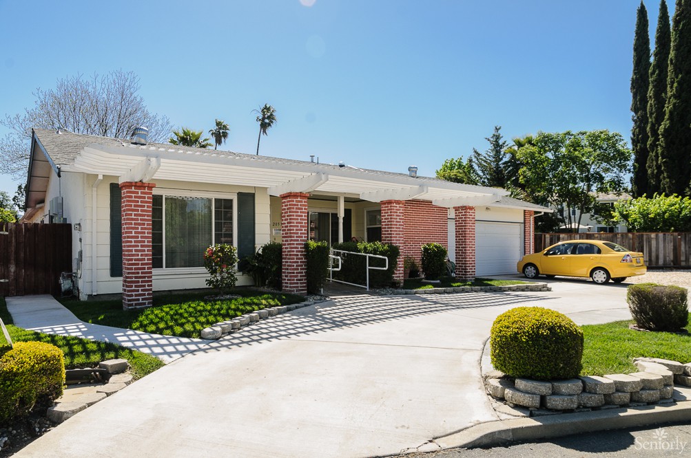 A sunny view of a suburban house with a well-maintained driveway and landscaping.