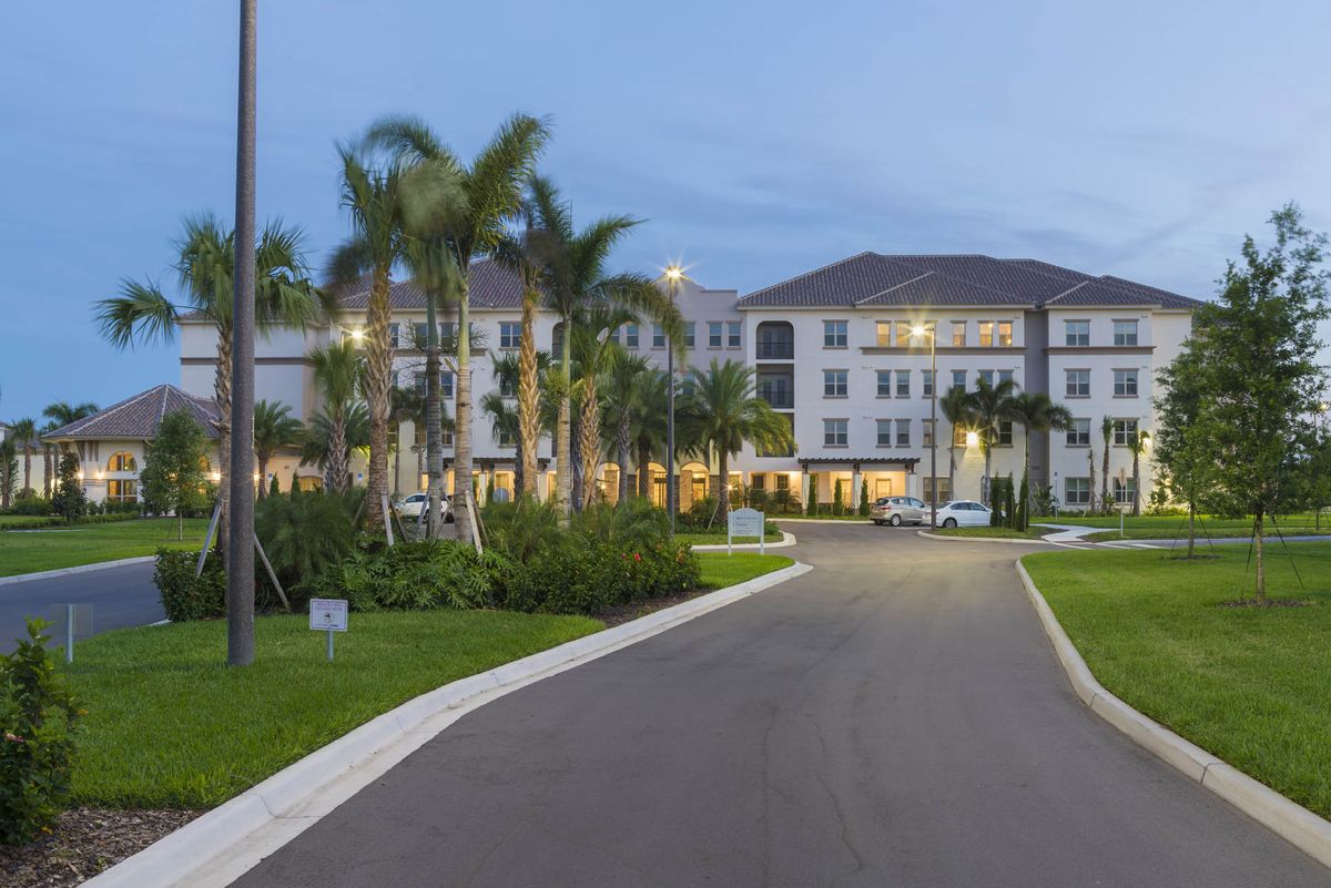 A residential apartment complex surrounded by palm trees in the evening light.