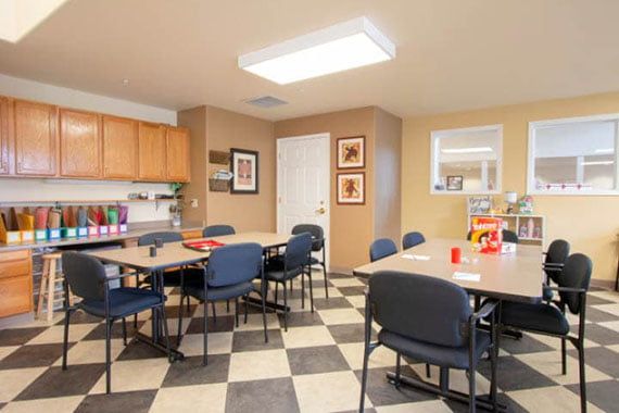 A classroom with tables and chairs arranged in a checkered-floor space.