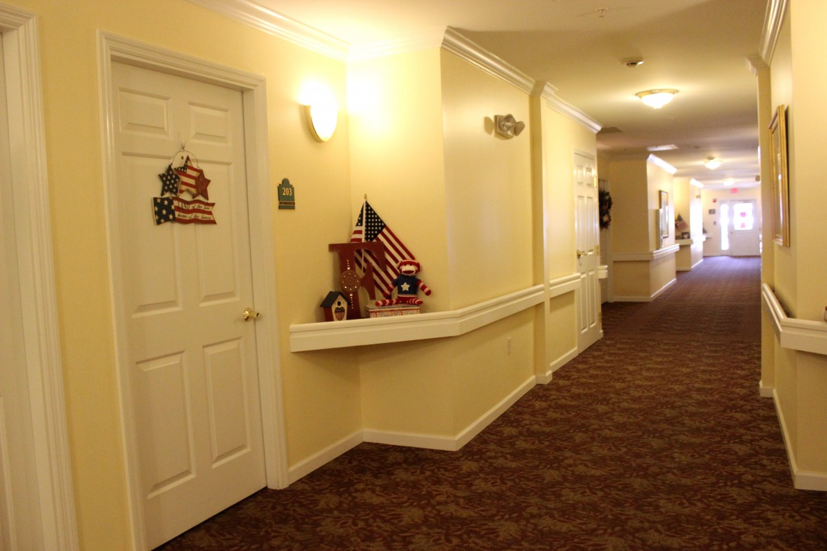 A well-lit hallway with decorated doors and carpeted flooring.