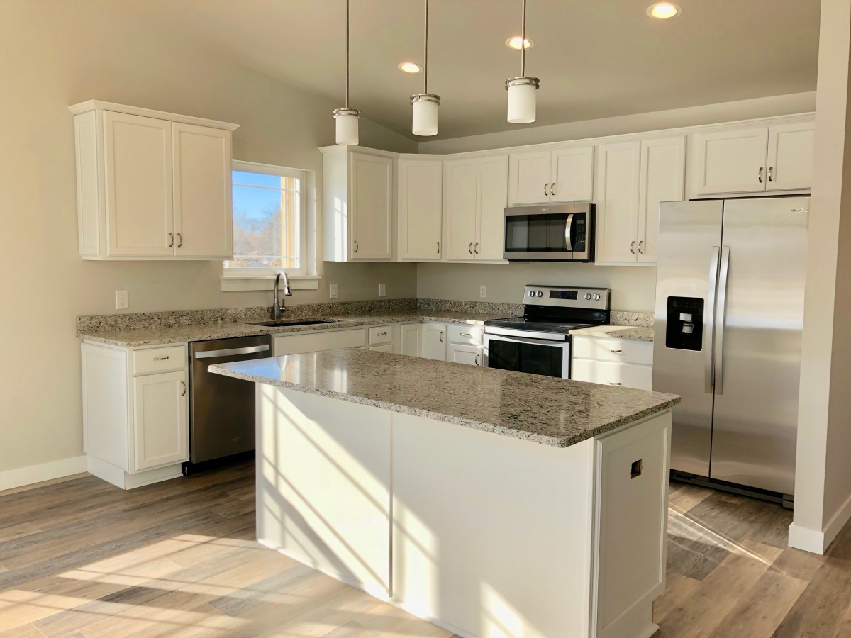 A modern kitchen with white cabinets and stainless steel appliances.