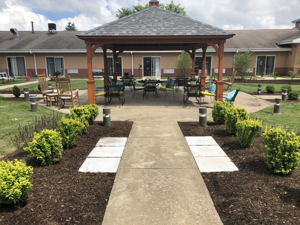 A well-maintained garden with a central pathway leading to a gazebo, surrounded by lush plants and outdoor seating.