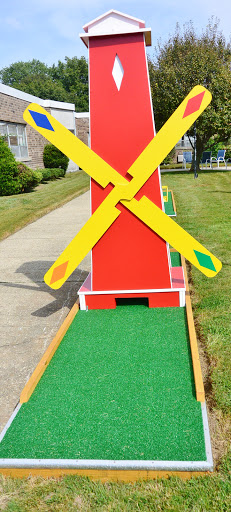 A vibrant windmill structure at a mini golf course, inviting players to enjoy a fun game in a scenic outdoor setting.