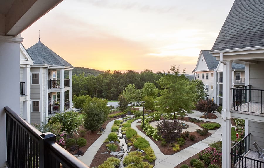 A picturesque view of a residential area with landscaped gardens at sunset.