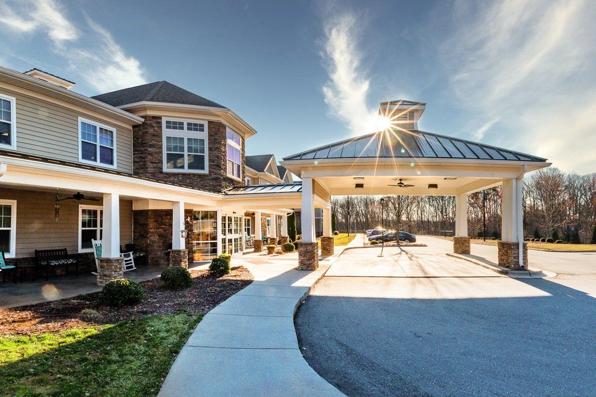 A modern residential building with a covered driveway and sunlight streaming through the sky.