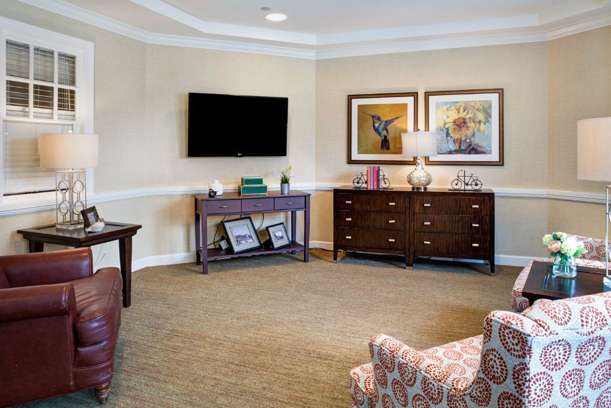 A cozy living room with a television, artwork on the walls, and comfortable furniture.