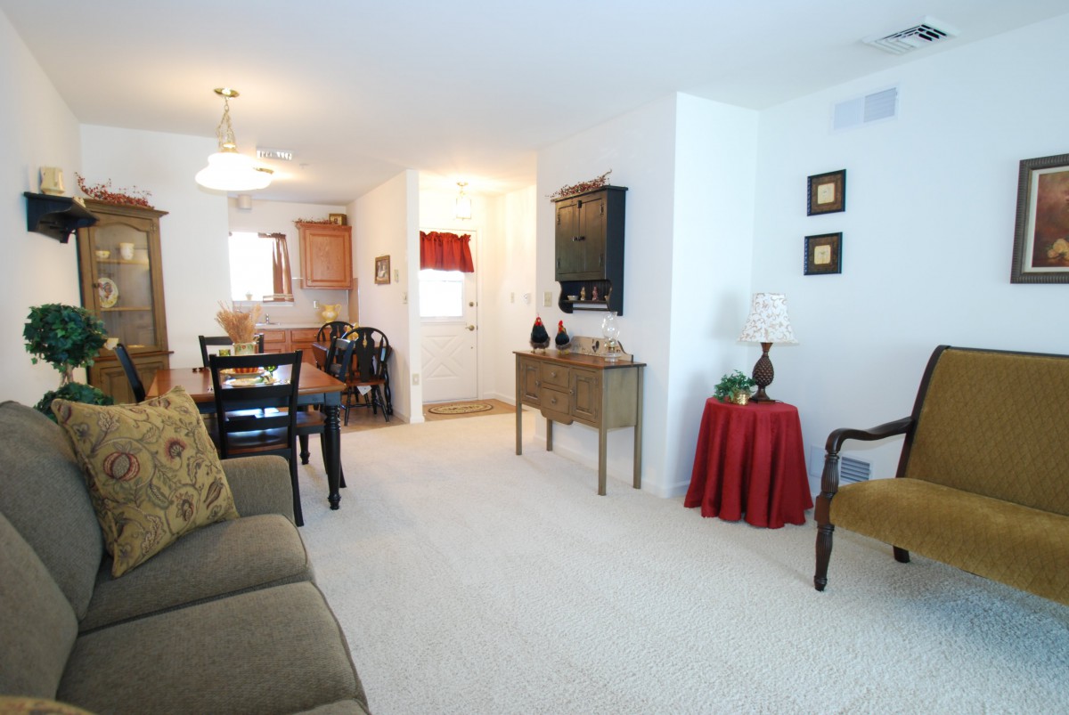 A well-lit living room with a dining area, featuring comfortable furnishings and tasteful decor.