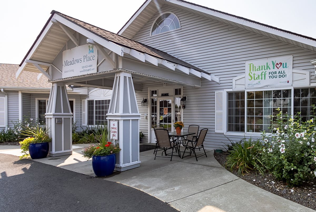 The image shows the entrance of a building with outdoor seating and signage.