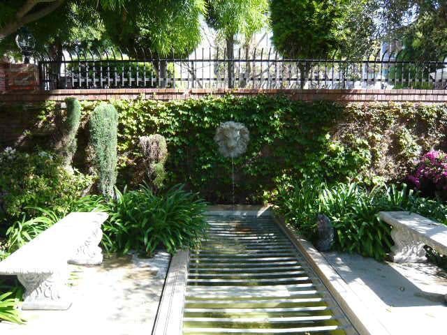 A tranquil garden scene with a water feature surrounded by lush greenery.