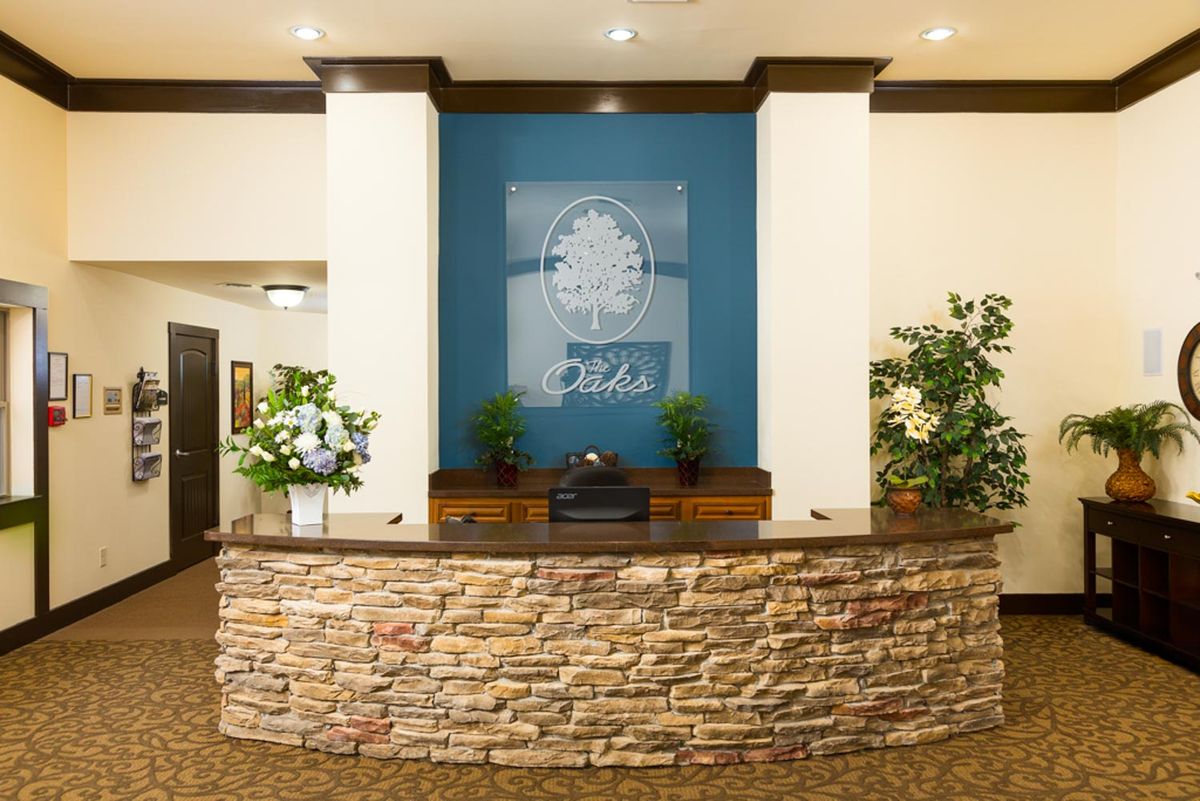 Hotel lobby reception area with a stone wall and decorative plants.