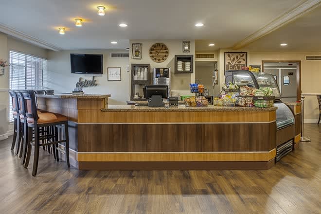 A cozy coffee shop interior featuring a wooden counter, seating area, and an assortment of snacks.
