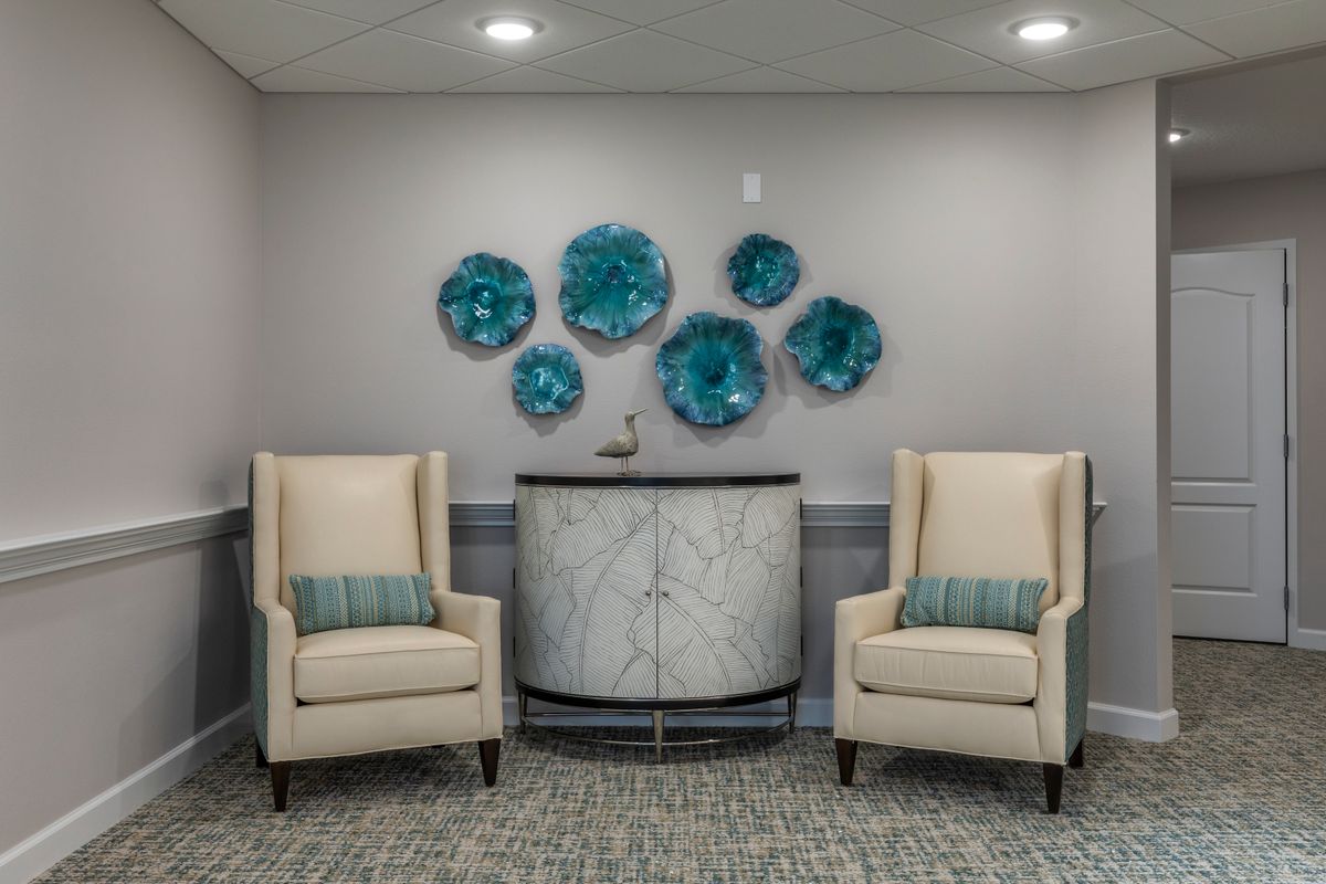 A stylish seating area with two beige chairs and blue wall art.