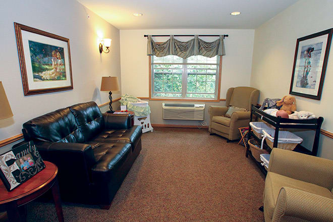 A cozy living room with a sofa, armchair, and a window with curtains.