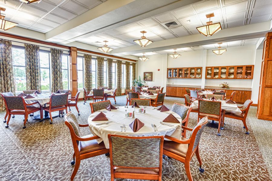 An elegant dining room with neatly arranged tables and chairs, featuring large windows and stylish decor.