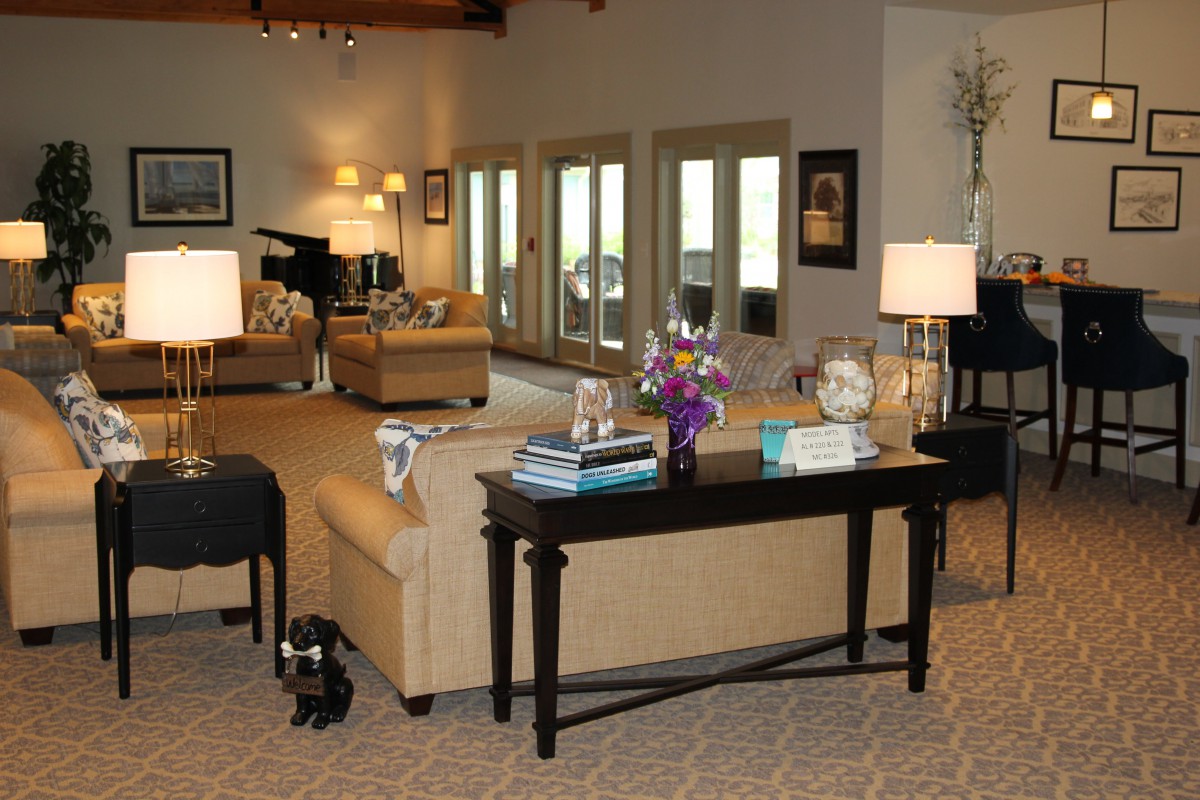 A spacious living room featuring comfortable sofas, a central table adorned with decor items, and large windows providing ample natural light.
