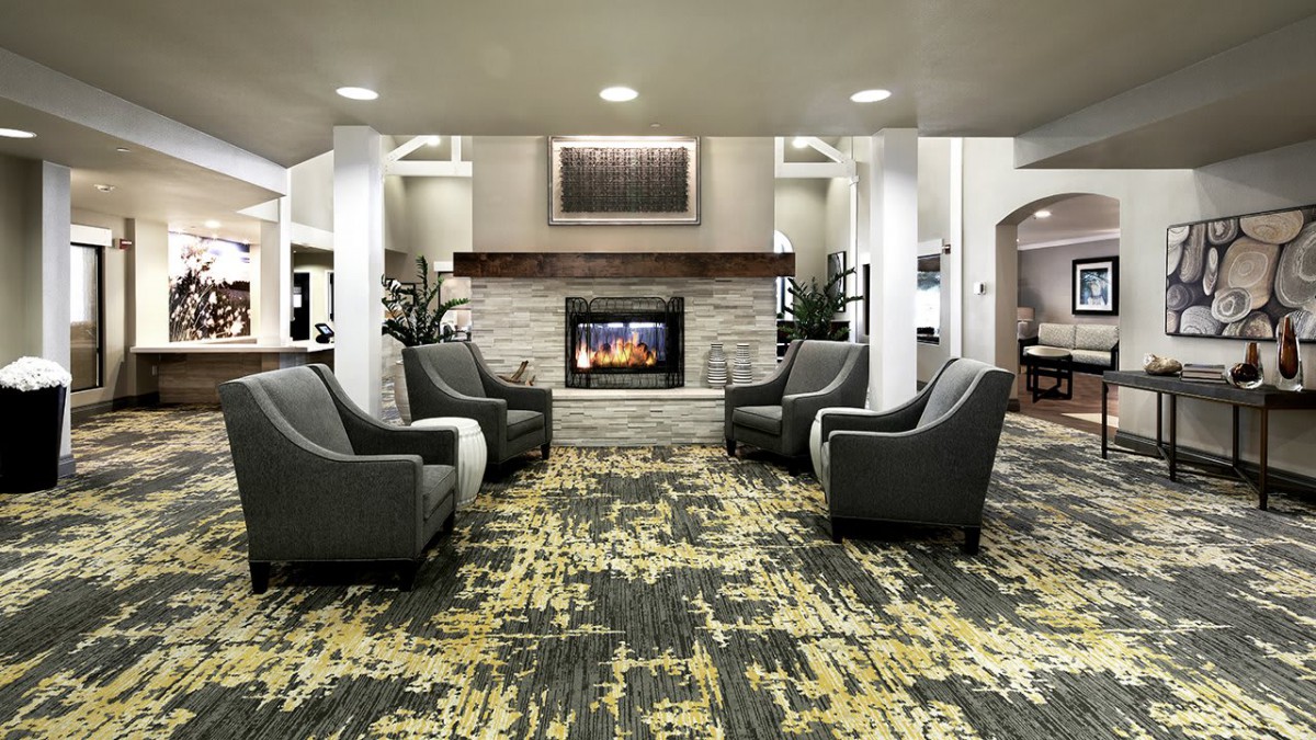 A modern lobby featuring a cozy seating area with a fireplace and armchairs.
