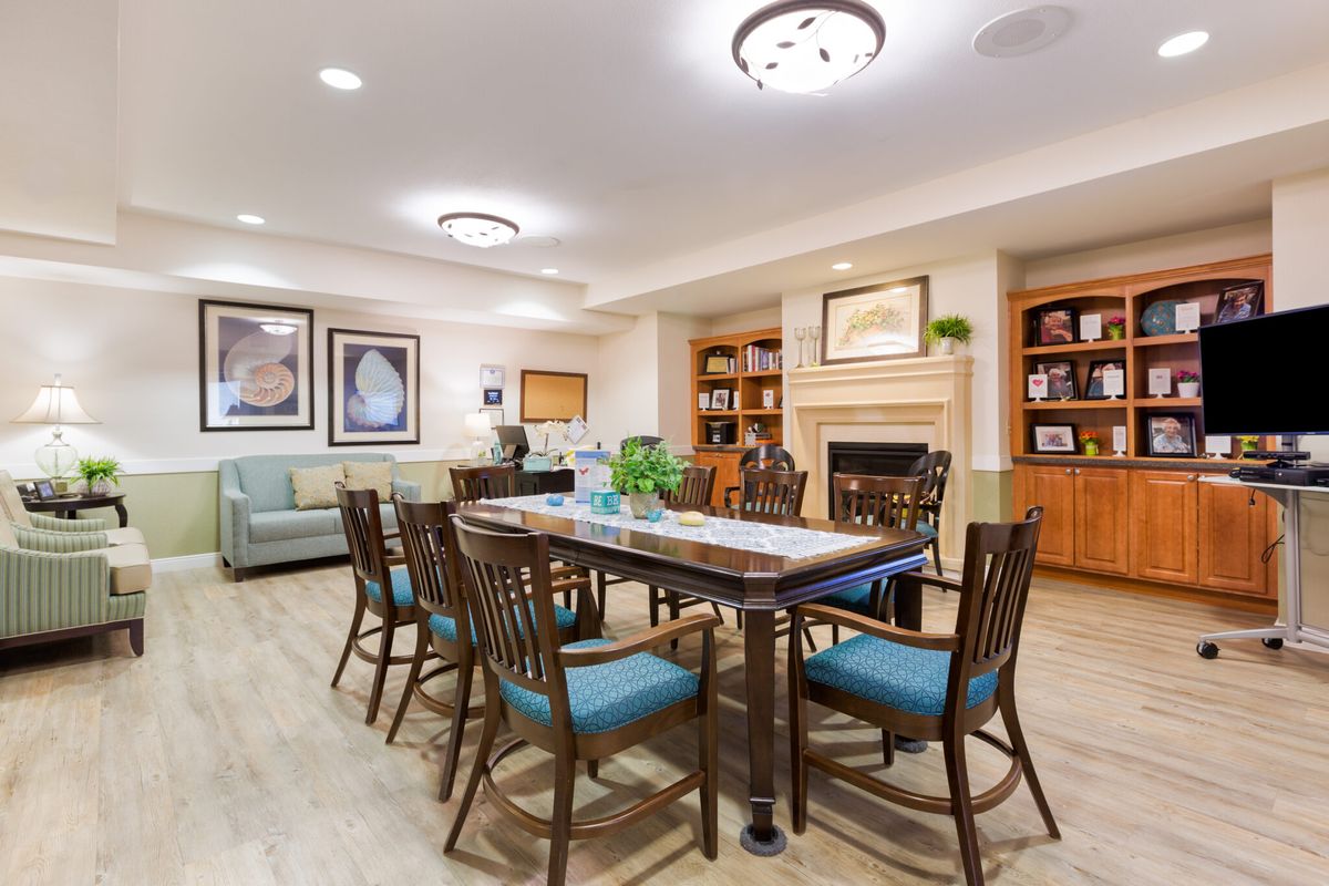 A modern dining area with a large table surrounded by chairs, featuring bookshelves and a fireplace.