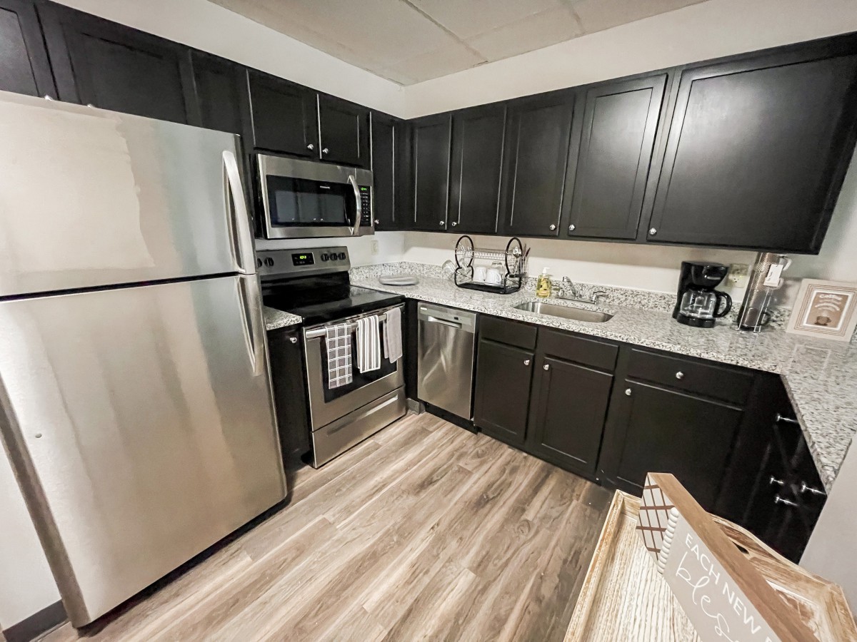 A modern kitchen with stainless steel appliances and dark cabinetry.