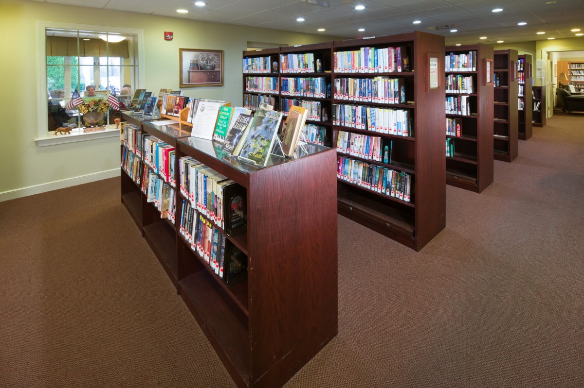 A cozy library room with rows of wooden bookshelves filled with books.