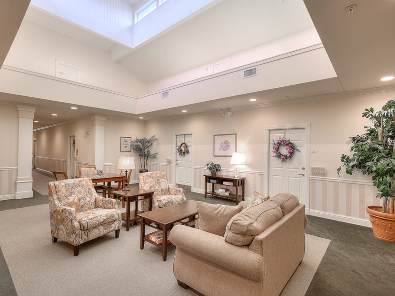 A cozy living room featuring comfortable sofas, a coffee table, and tasteful decorations with wreaths hung on doors.