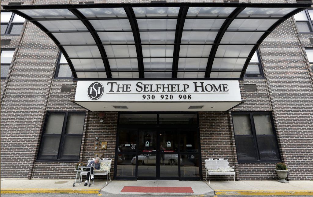 Entrance of The Selfhelp Home with a glass canopy and seating area.