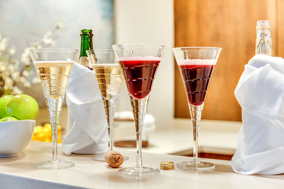 Elegant glasses filled with champagne and a red cocktail, set on a bar for a celebration.