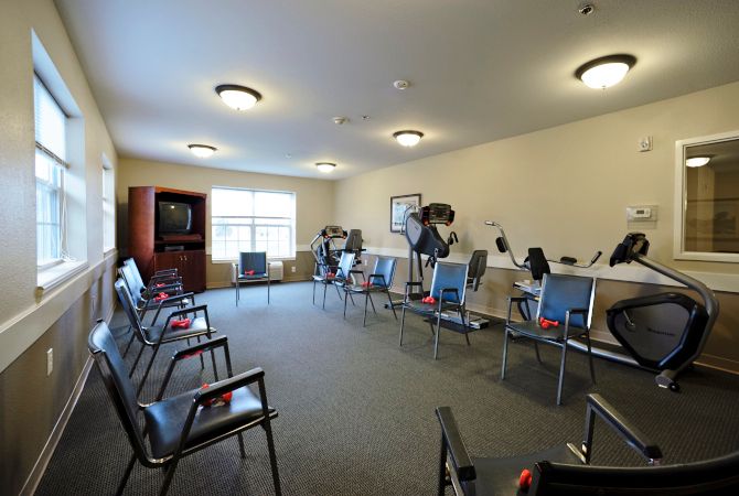 A well-lit exercise room with chairs and stationary bikes arranged in a spacious layout.