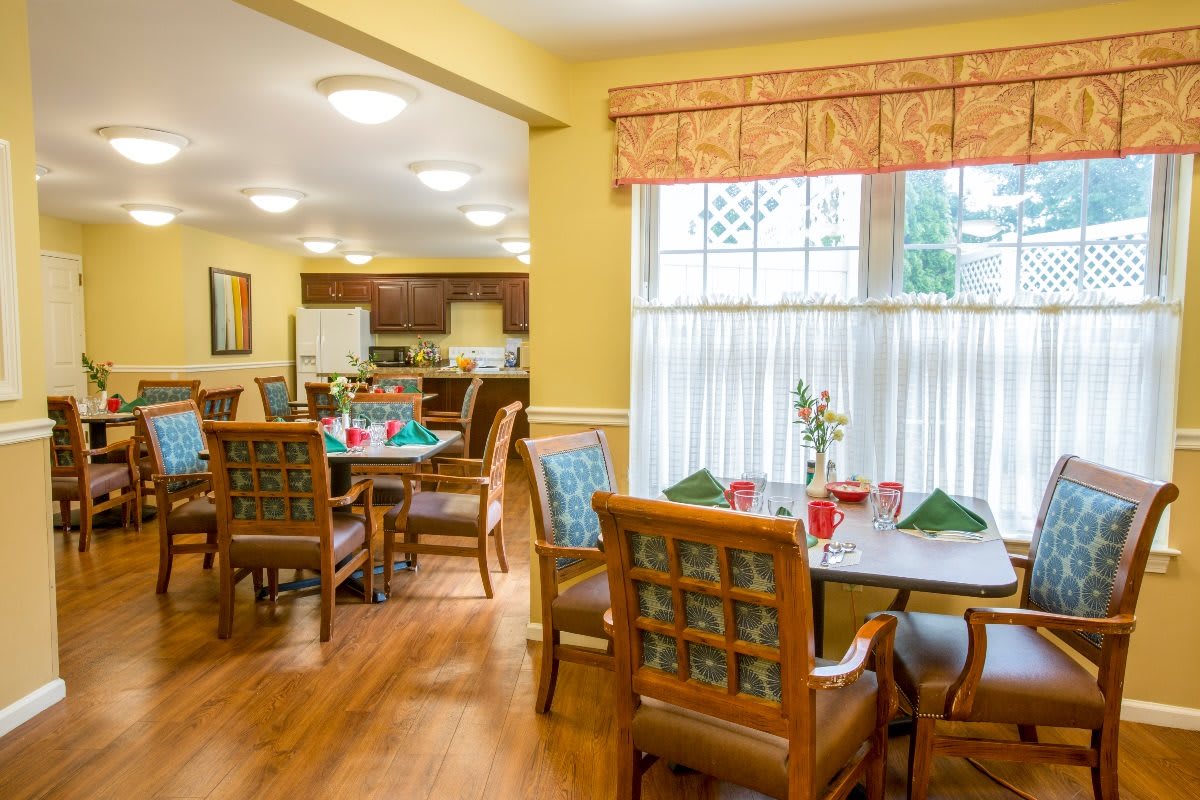 A well-lit dining room with neatly arranged tables and chairs.