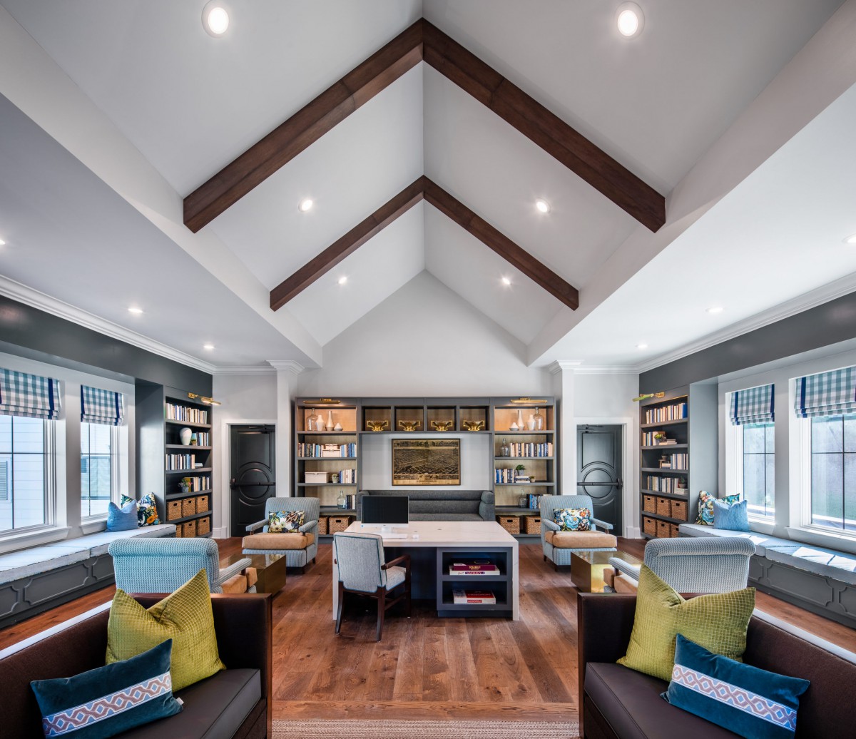 A modern living room with vaulted ceilings, wooden beams, and ample natural light.