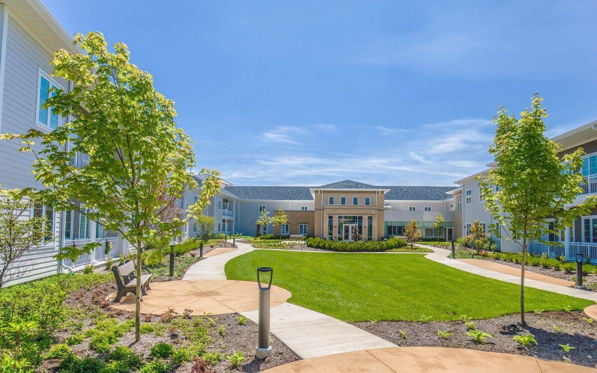 A view of a modern building surrounded by landscaped gardens and pathways under a clear blue sky.