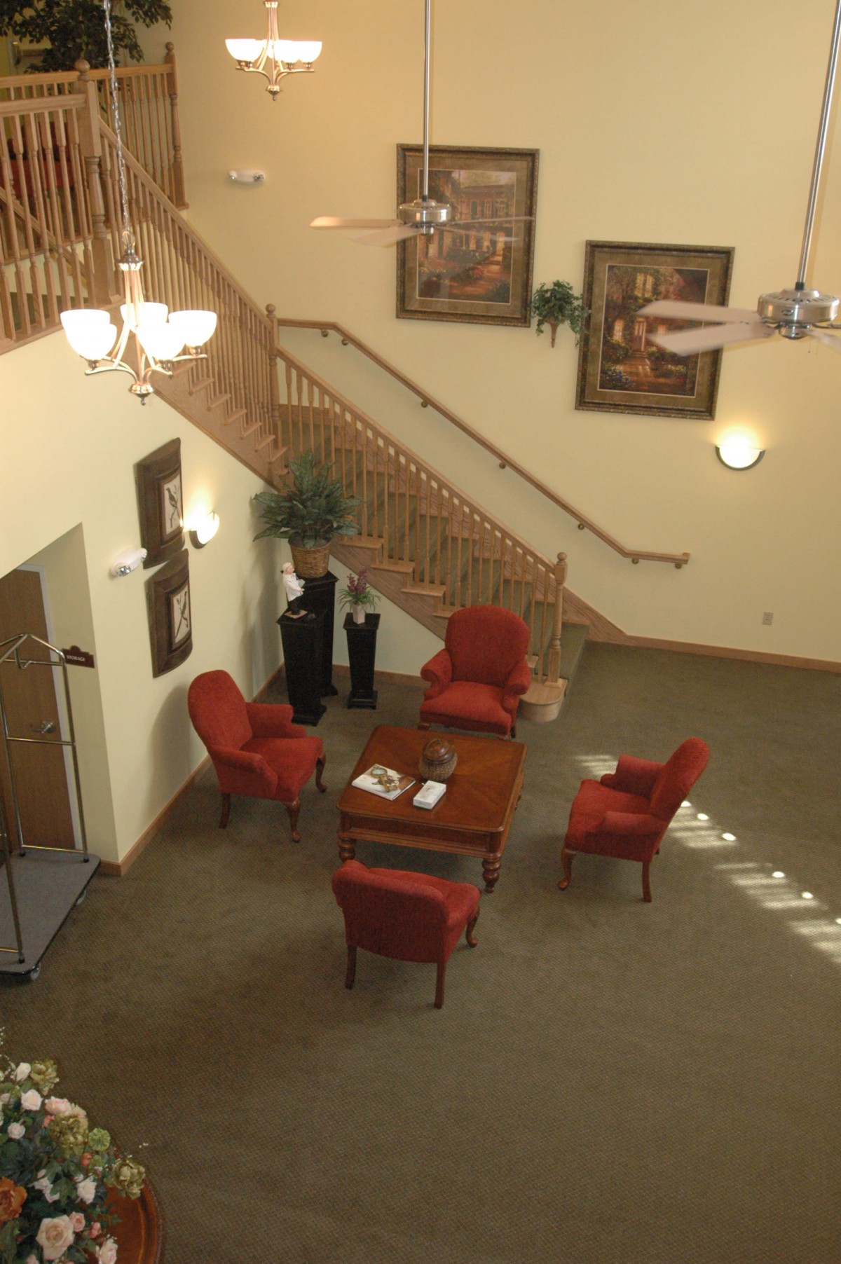 A cozy lobby area featuring a wooden staircase, red chairs, and a central table.