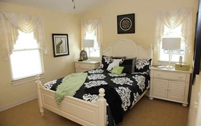 A cozy bedroom with elegant black and white bedding, complemented by light-colored furniture.