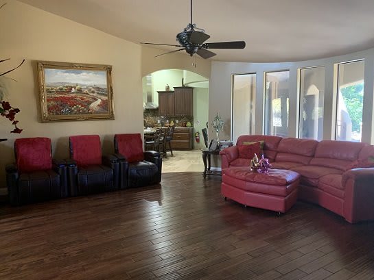 A spacious living room with red sofas, wood flooring, and a ceiling fan.