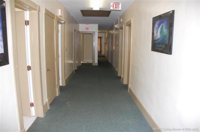 A long, carpeted hallway with multiple doors on both sides.