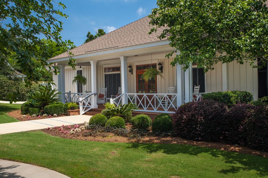 A charming house with a front porch and well-maintained garden on a sunny day.