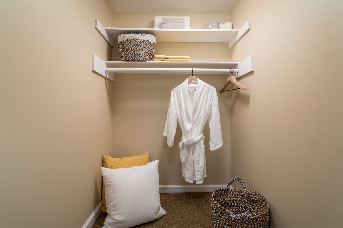 A well-organized closet with a robe hanging and baskets on shelves.