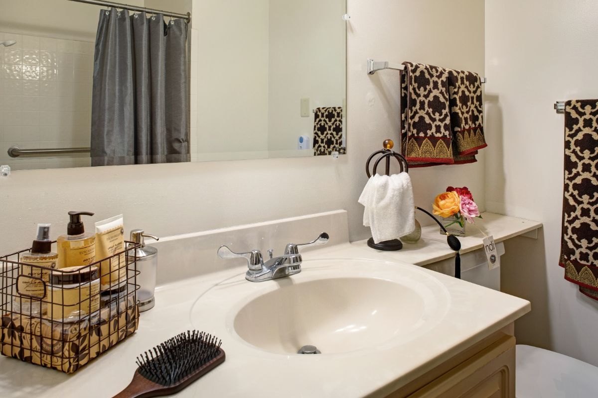 A tidy bathroom with a sink, mirror, and decorative towels.