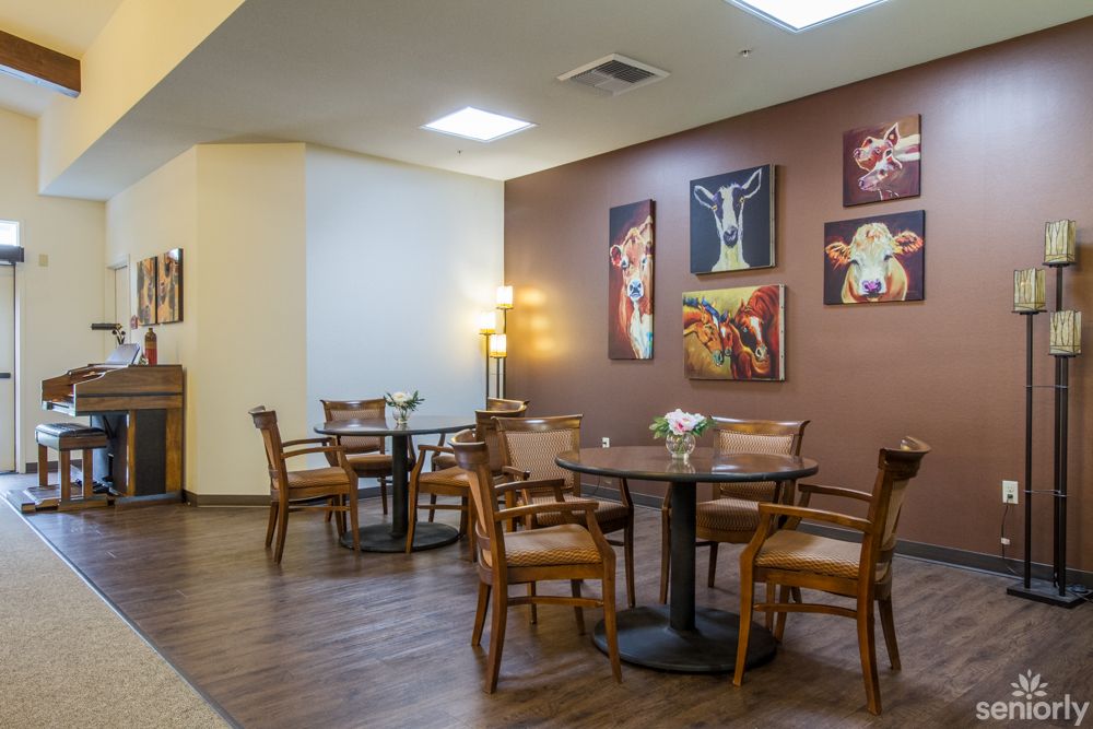 A cozy dining area with tables, chairs, and artistic wall decorations.