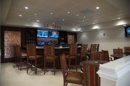 An empty bar area with high chairs, a counter, and multiple televisions.