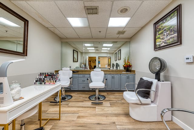A modern beauty salon interior featuring chairs, mirrors, and a makeup station.