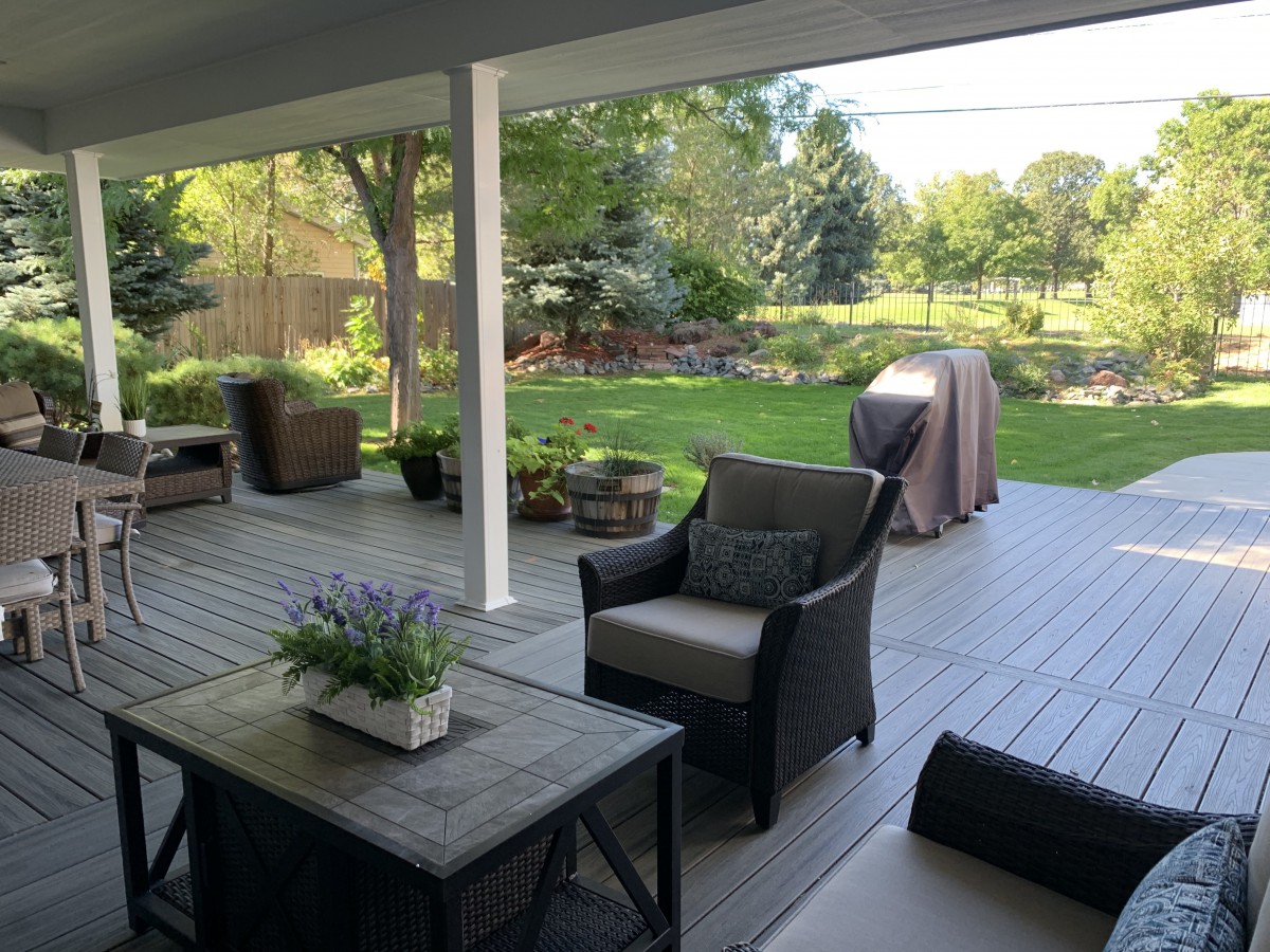 A cozy patio overlooking a lush garden, featuring comfortable outdoor furniture and potted plants.