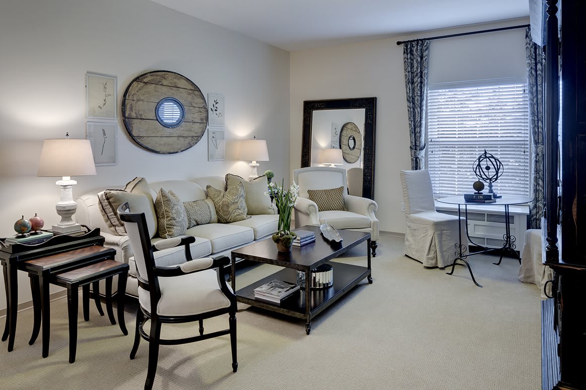 A cozy living room featuring a comfortable sofa, stylish chairs, a coffee table, and decorative elements such as mirrors and lamps.