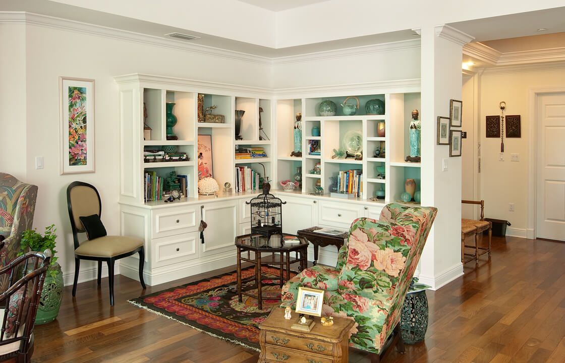 A cozy living room corner with built-in white bookshelves, a floral armchair, and decorative accents.