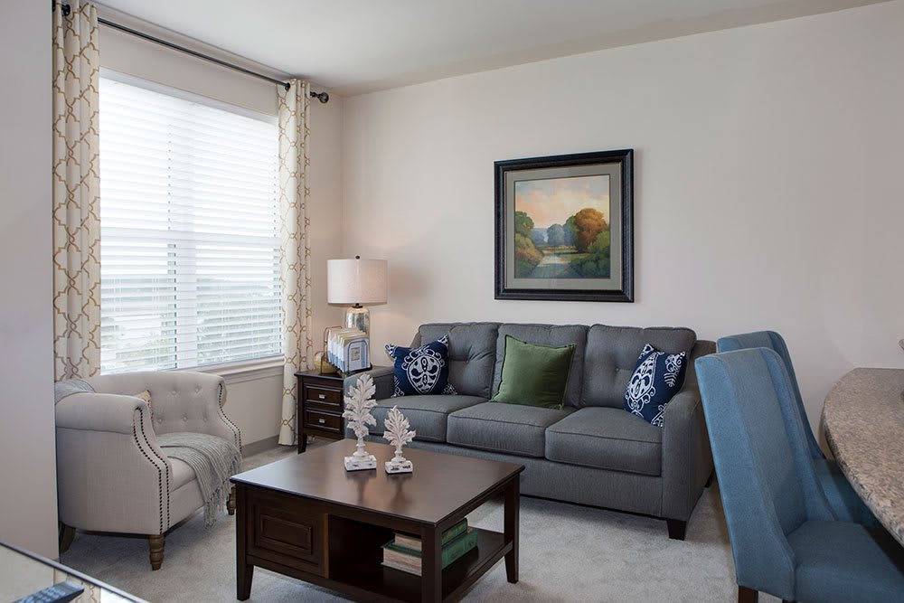 A cozy and well-decorated living room with a sofa, coffee table, lamp, and artwork on the wall.