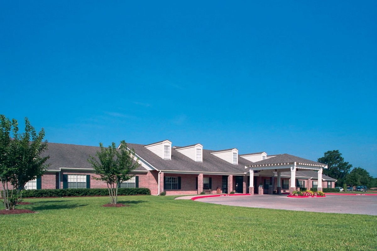 A residential building with a well-maintained lawn under a clear blue sky.