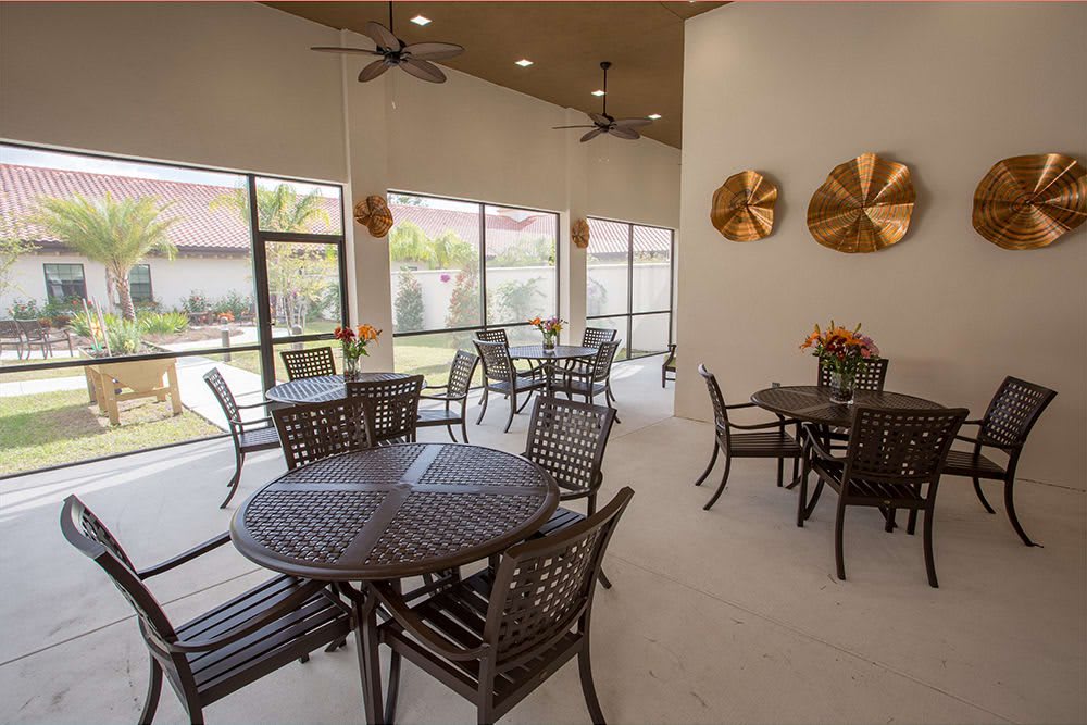 A spacious patio area with tables and chairs, featuring large windows and decorative wall pieces.