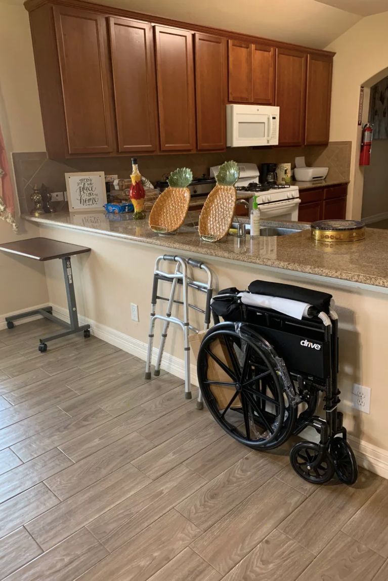 A kitchen with mobility aids including a wheelchair and a walker by the countertop.